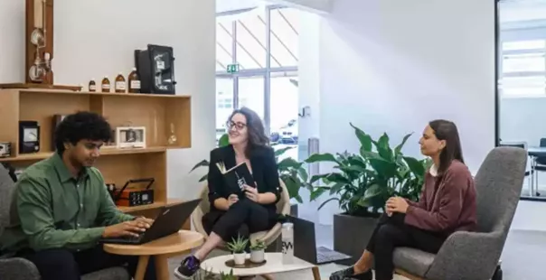 EDP employees at a meeting in a room lit by windows, wooden furniture and surrounding plants