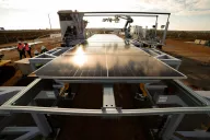 solar panel installation site using robotics, featuring mounted panels and a robotic arm assisting with positioning, while workers in safety gear oversee the process